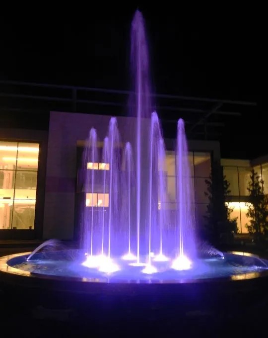 Fontana dinamica con getti illuminati di viola in notturna