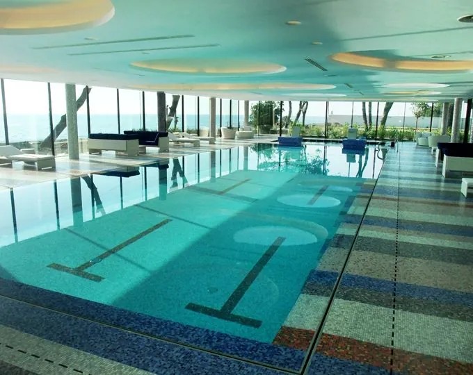 Piscina interna con decori a mosaico e vetrate panoramiche