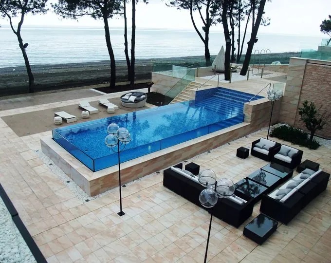 Piscina a sfioro con pareti in vetro fronte mare